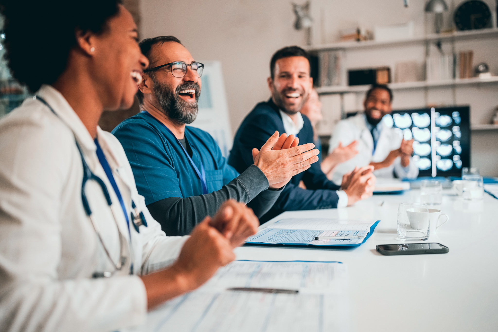 A group of medical staff clapping in a meeting.